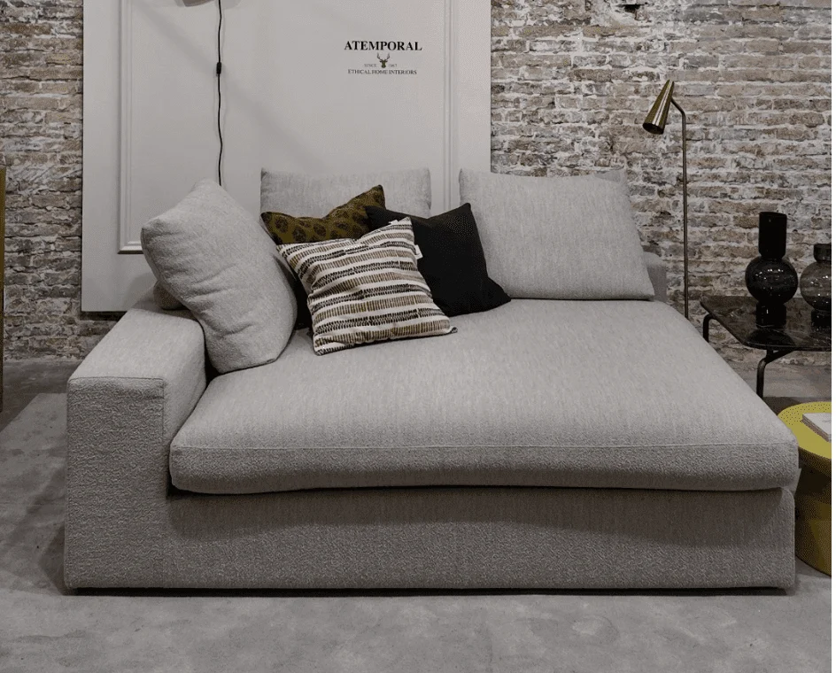 Chaise longue gris con cojines en una exposición